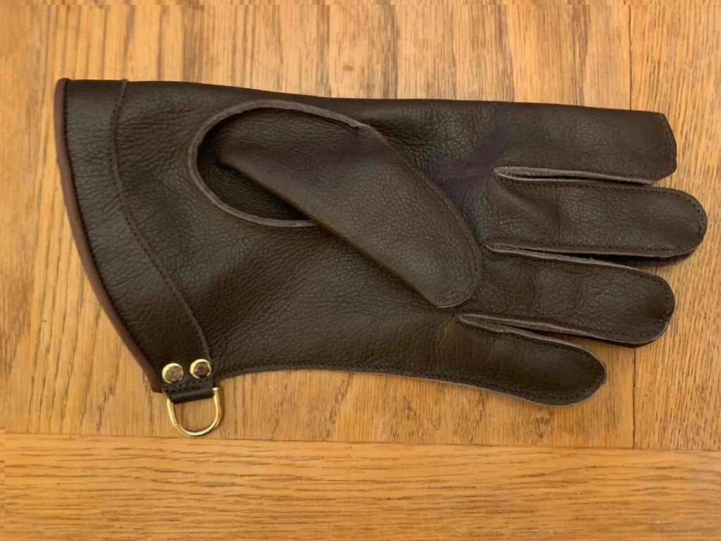 machine sewn falconry gloves displayed on a wooden surface, showing quality leather and design features.