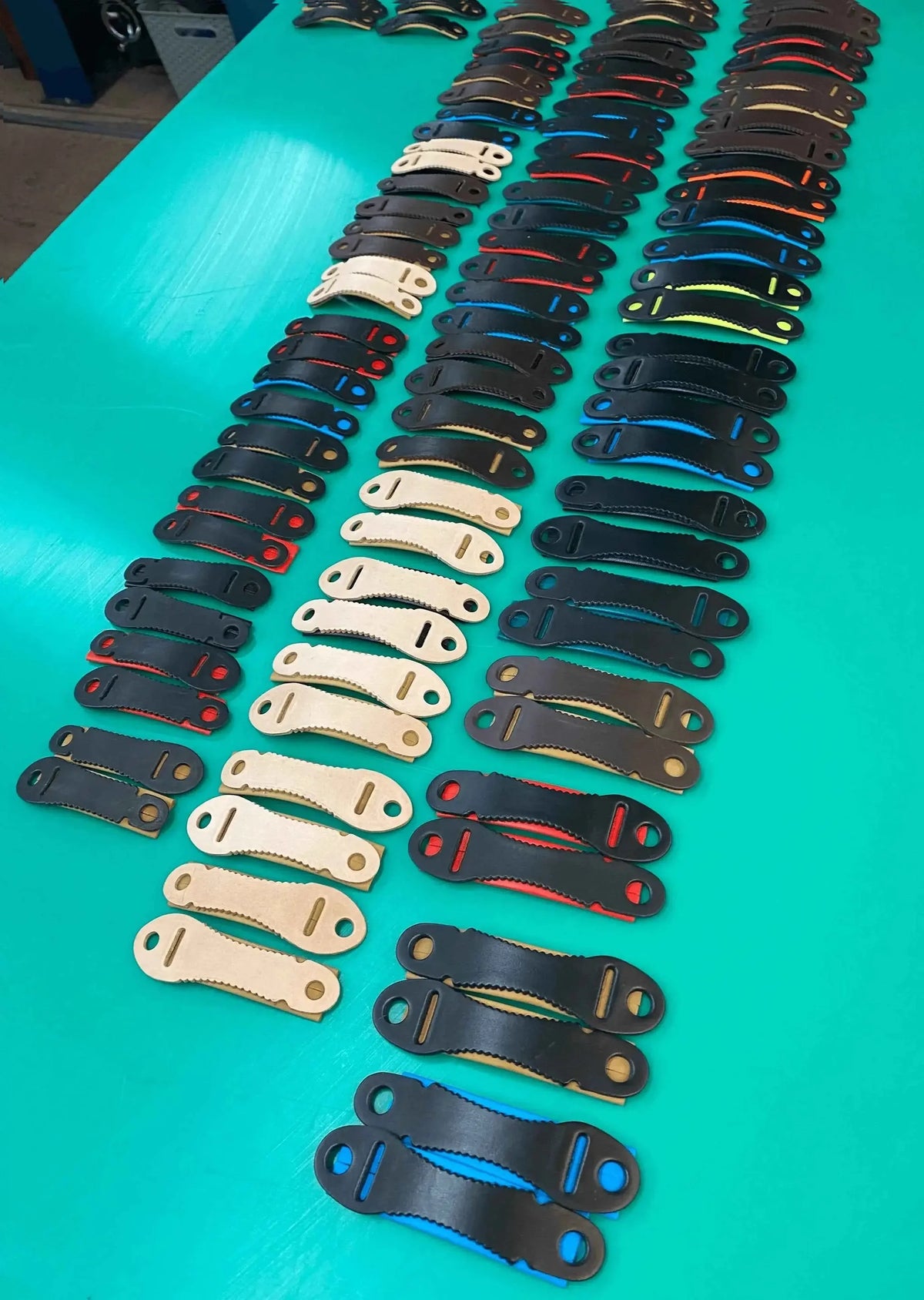 Various falconry aylmeri anklets in different colors laid out on a green table for bird comfort and strength.
