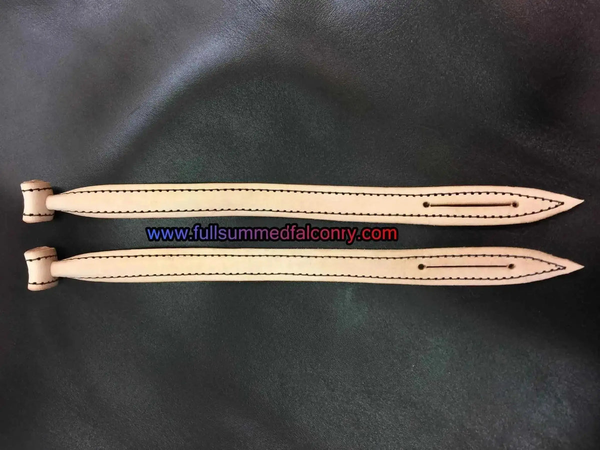 Natural colored leather jesses with dark edge stitching on dark background